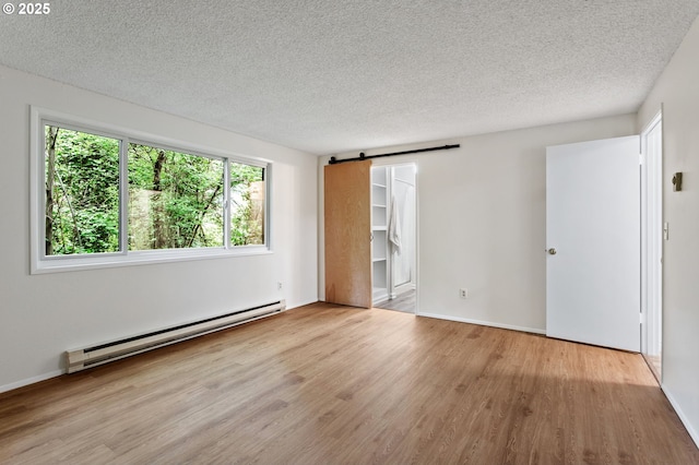 7124 SW Murray Blvd, Beaverton, OR 97008 - unfurnished bedroom with baseboard heating, a textured ceiling, wood finished floors, a barn door, and baseboards