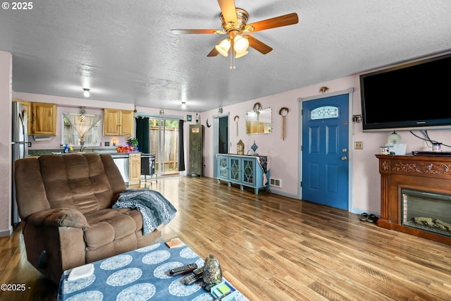 5053 NE 50th St, Neotsu, OR 97364 - living room featuring a textured ceiling, a ceiling fan, light wood-style flooring, and a fireplace