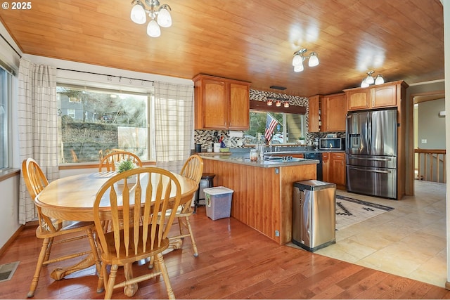 kitchen featuring appliances with stainless steel finishes, wood ceiling, a peninsula, and light wood finished floors