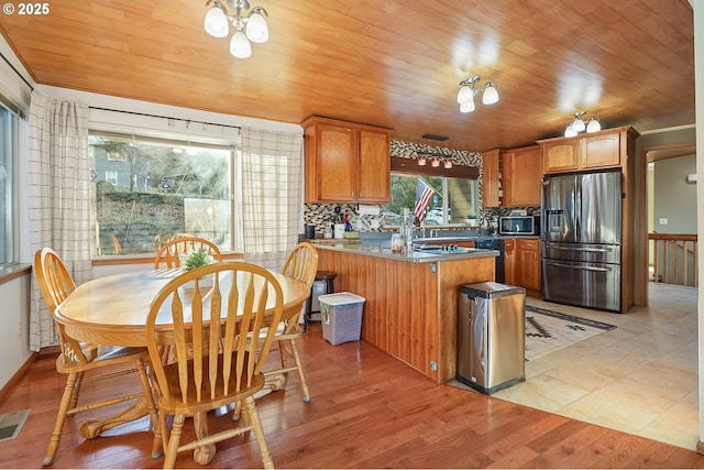 211 W 16th St, The Dalles, OR 97058 - kitchen featuring appliances with stainless steel finishes, a peninsula, brown cabinetry, wooden ceiling, and light wood-type flooring