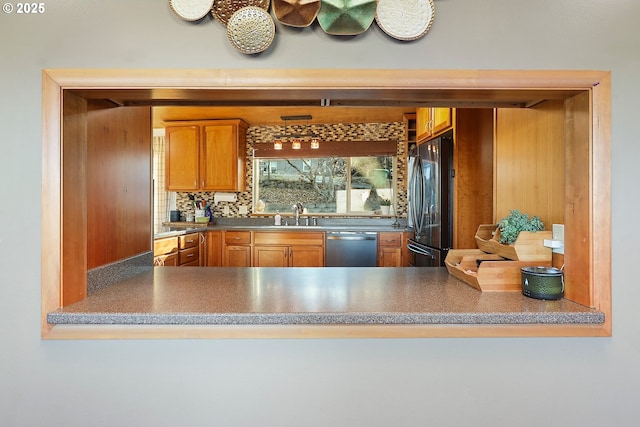 kitchen featuring stainless steel appliances, a peninsula, a sink, and decorative backsplash