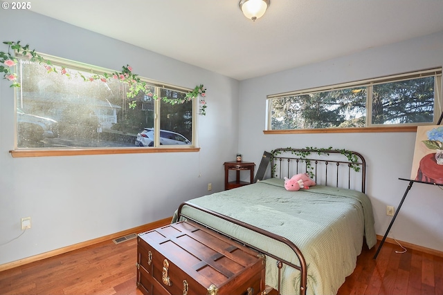 bedroom featuring visible vents, baseboards, and wood finished floors