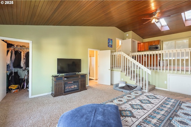 carpeted living area featuring lofted ceiling with skylight, wooden ceiling, baseboards, and stairs