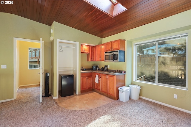 kitchen with light carpet, stainless steel appliances, a skylight, wood ceiling, and baseboards