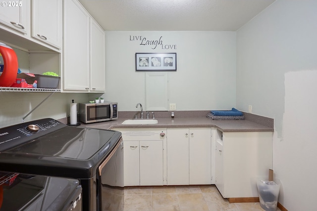 clothes washing area with cabinet space, washing machine and dryer, and a sink