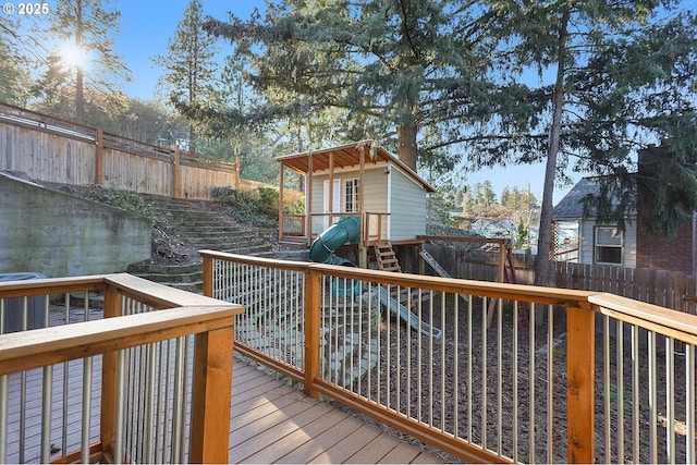 wooden deck featuring a playground and a fenced backyard