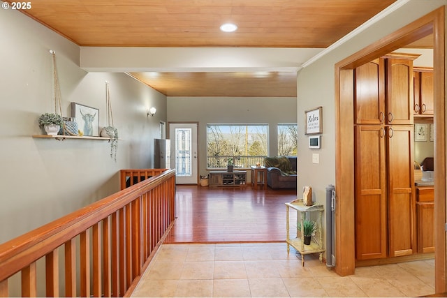 hall with light tile patterned flooring, an upstairs landing, wood ceiling, and crown molding