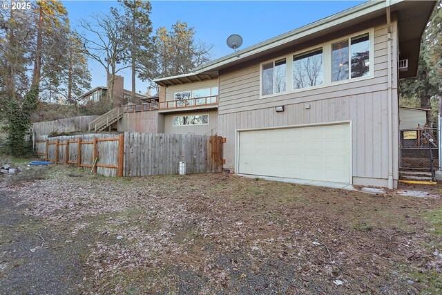 rear view of property featuring an attached garage and fence