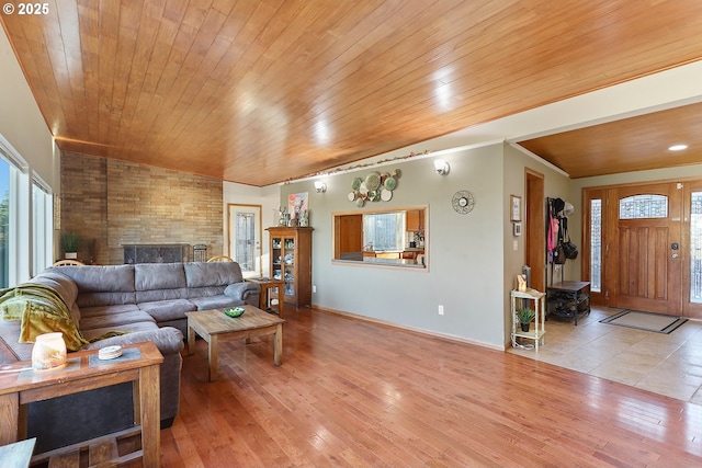 living area with ornamental molding, wood ceiling, baseboards, and wood finished floors