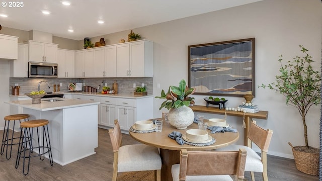9336 SE Middleton St, Happy Valley, OR 97086 - kitchen featuring stainless steel microwave, dark wood finished floors, white cabinetry, backsplash, and a breakfast bar area