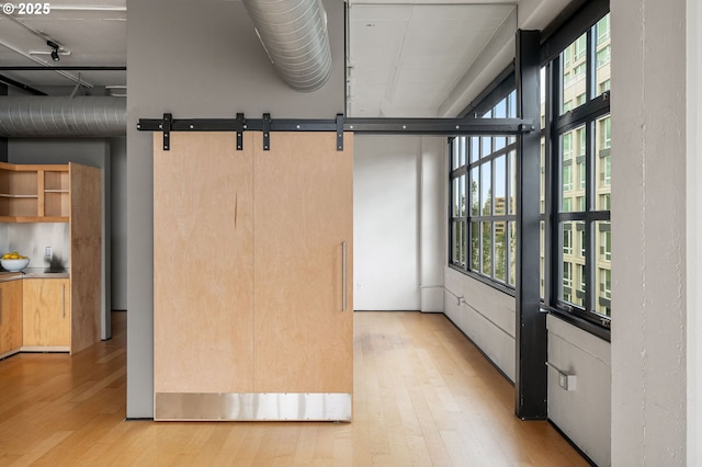 unfurnished sunroom featuring a barn door and plenty of natural light