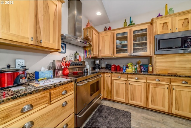 48482 E Meadow Way, Oakridge, OR 97463 - kitchen featuring wall chimney exhaust hood, stainless steel appliances, dark stone counters, glass insert cabinets, and recessed lighting