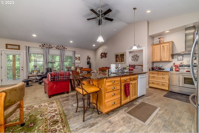 48482 E Meadow Way, Oakridge, OR 97463 - kitchen with range with two ovens, white dishwasher, wall chimney exhaust hood, a kitchen breakfast bar, and ceiling fan