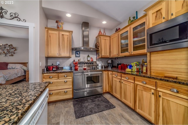 48482 E Meadow Way, Oakridge, OR 97463 - kitchen featuring wall chimney range hood, appliances with stainless steel finishes, vaulted ceiling, dark stone counters, and glass insert cabinets