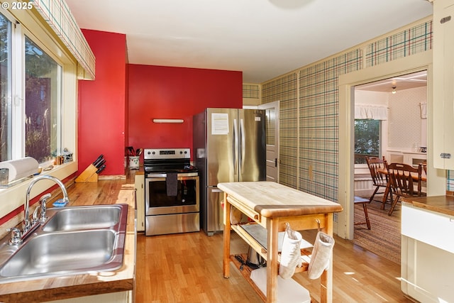 kitchen featuring stainless steel appliances, plenty of natural light, sink, and light hardwood / wood-style flooring