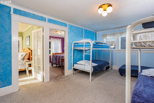 carpeted bedroom featuring crown molding, a textured ceiling, and french doors