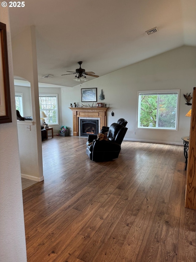 living area featuring visible vents, a tile fireplace, wood finished floors, ceiling fan, and vaulted ceiling