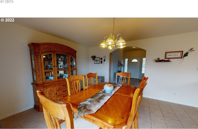 dining space featuring baseboards, arched walkways, an inviting chandelier, and light tile patterned flooring