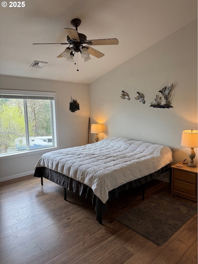 bedroom featuring a ceiling fan, wood finished floors, and visible vents