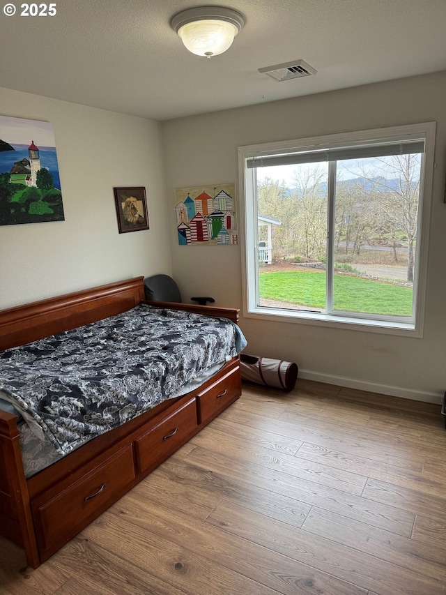 bedroom with multiple windows, baseboards, visible vents, and wood-type flooring