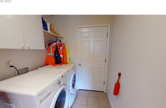 laundry room featuring light tile patterned floors, cabinet space, and washing machine and clothes dryer