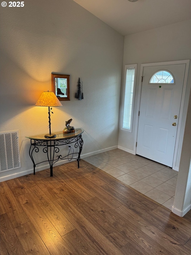 foyer entrance featuring visible vents, baseboards, and wood finished floors