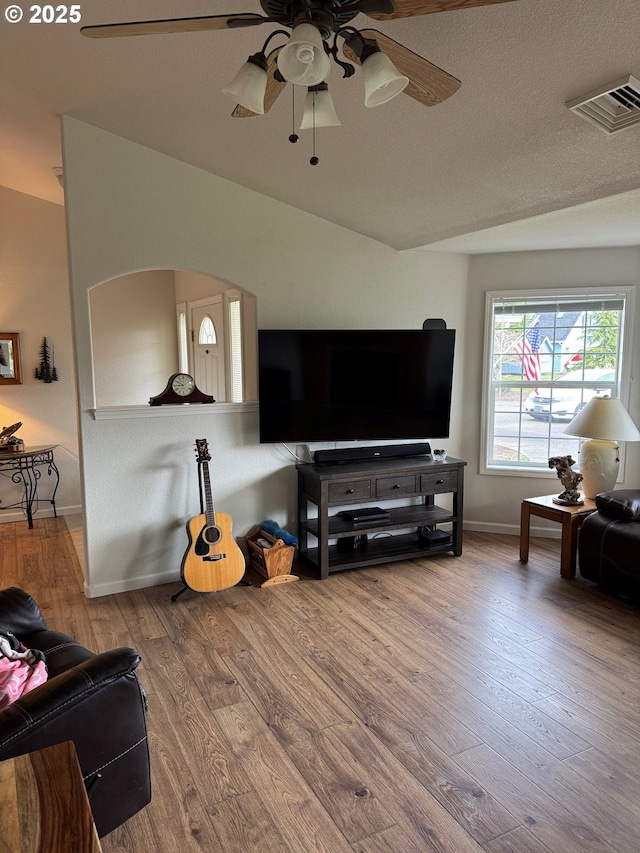 living area with visible vents, baseboards, ceiling fan, wood finished floors, and a textured ceiling