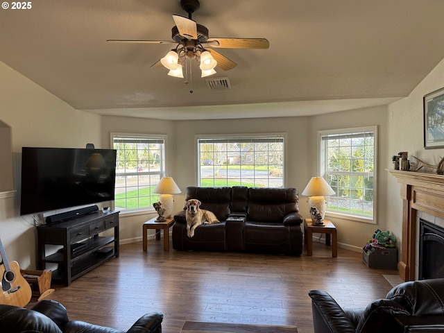 living area with visible vents, baseboards, ceiling fan, a fireplace, and wood finished floors