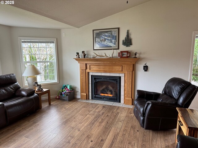 living area with a fireplace, vaulted ceiling, wood finished floors, and baseboards