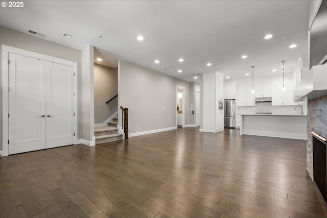 3825 NW 74th Ave Unit 59, Camas, WA 98607 - unfurnished living room featuring stairs, recessed lighting, dark wood-style flooring, baseboards, and a sink