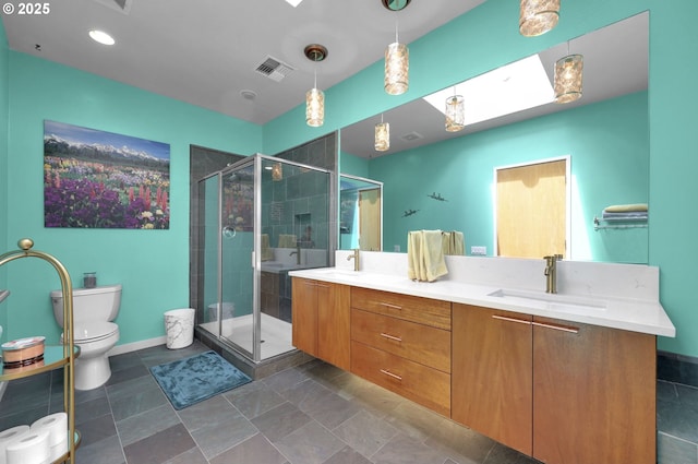 bathroom with double vanity, a shower stall, toilet, and baseboards