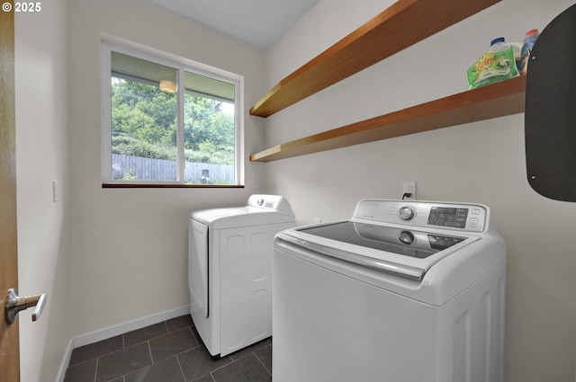 laundry room with washer and dryer, dark tile patterned flooring, and baseboards