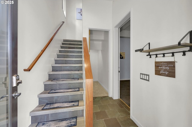 stairway featuring stone finish flooring and baseboards