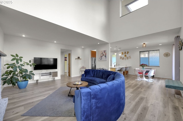 living room with light wood finished floors, recessed lighting, and a towering ceiling