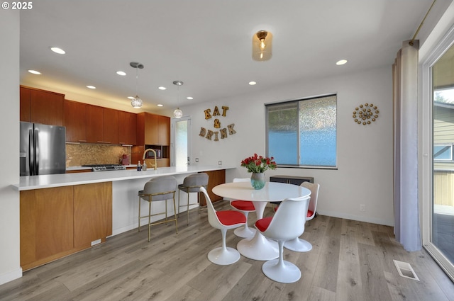 dining space featuring light wood finished floors, healthy amount of natural light, and recessed lighting