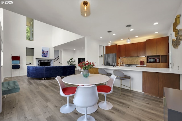 dining area with a fireplace, light wood-type flooring, and recessed lighting