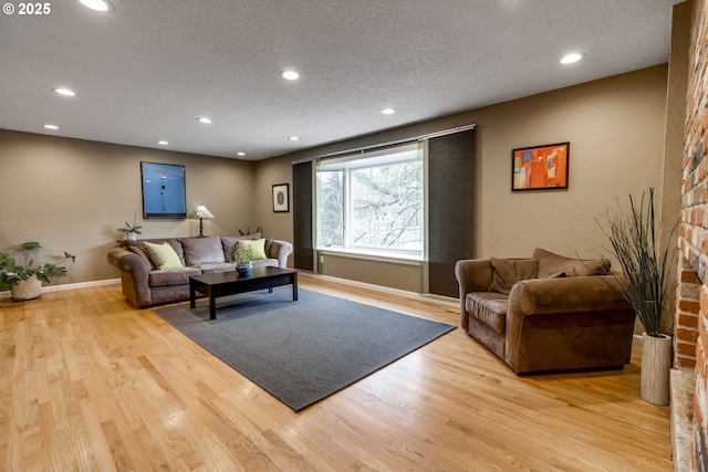 living room featuring light wood finished floors, baseboards, recessed lighting, a fireplace, and a textured ceiling