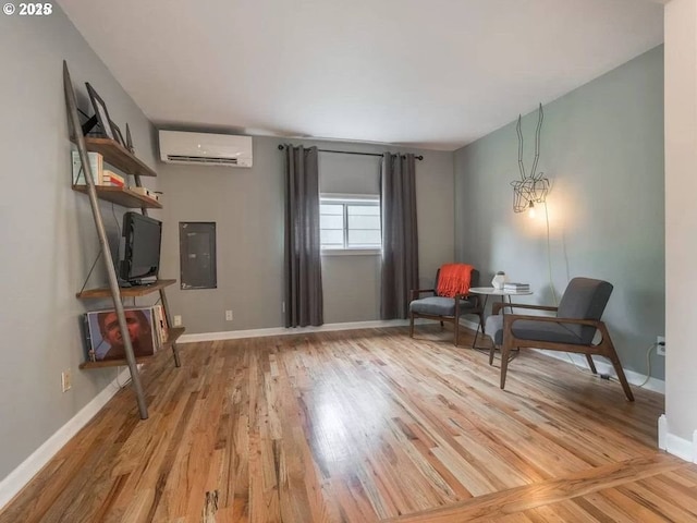 sitting room featuring electric panel, a wall unit AC, and light hardwood / wood-style flooring