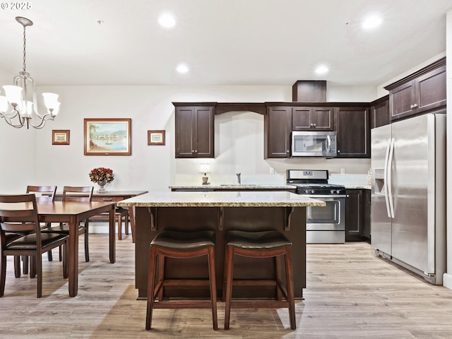 kitchen with dark brown cabinetry, hanging light fixtures, light hardwood / wood-style flooring, and appliances with stainless steel finishes