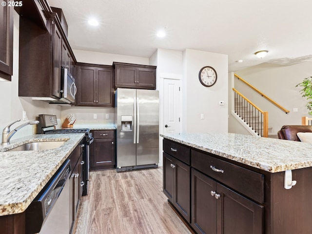 kitchen featuring appliances with stainless steel finishes, a center island, light hardwood / wood-style floors, and light stone countertops