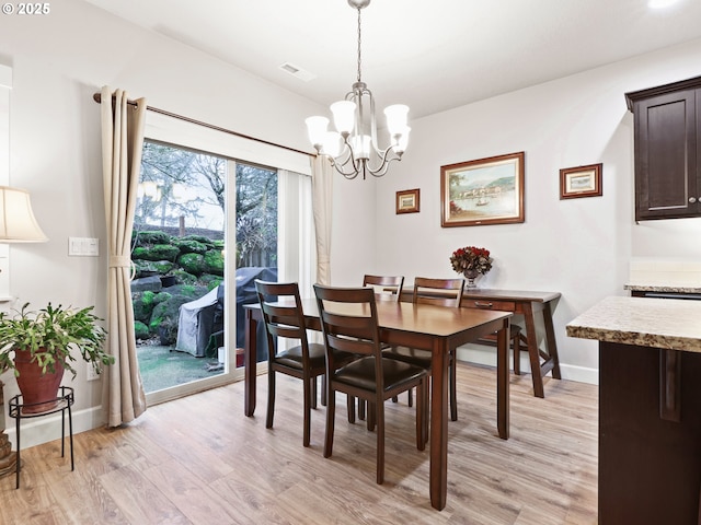 dining room with light hardwood / wood-style flooring and a chandelier