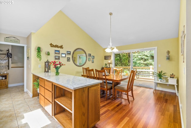 interior space with decorative light fixtures, open shelves, vaulted ceiling, brown cabinets, and baseboards