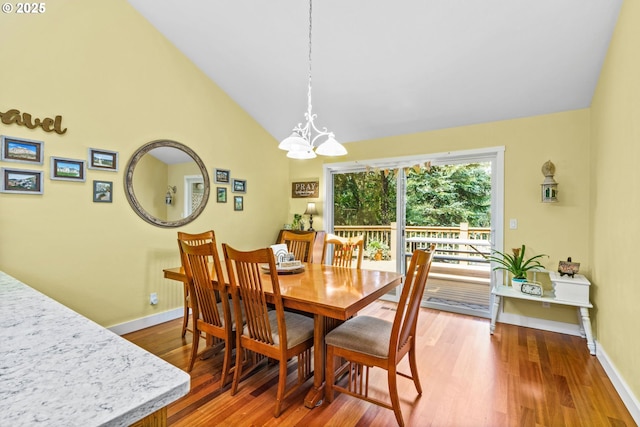 dining space featuring baseboards, an inviting chandelier, wood finished floors, and lofted ceiling