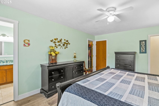 bedroom with connected bathroom, ceiling fan, a sink, light wood-style floors, and baseboards