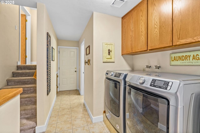 washroom featuring visible vents, washing machine and dryer, light tile patterned flooring, baseboards, and cabinet space