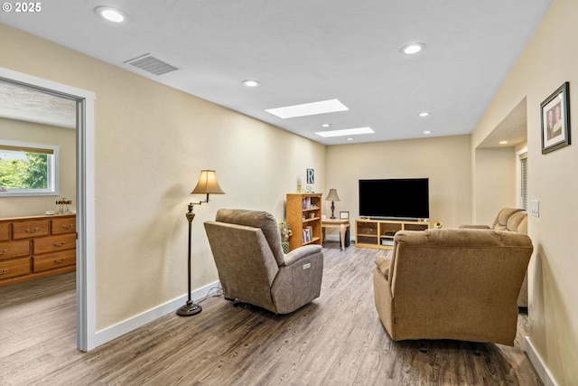 living area featuring visible vents, a skylight, wood finished floors, baseboards, and recessed lighting