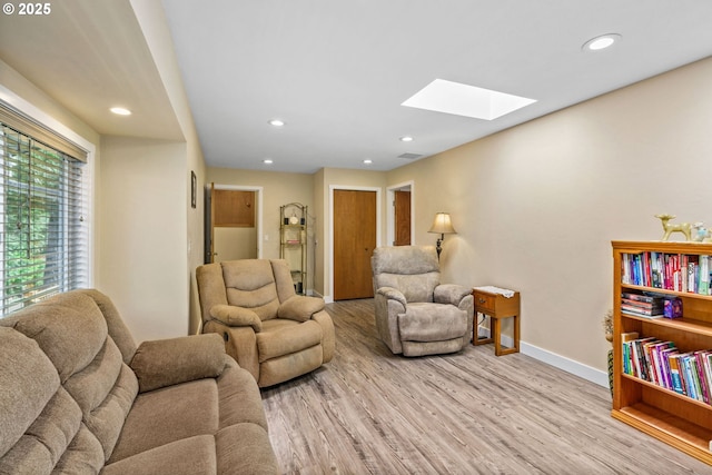 living room featuring a skylight, baseboards, recessed lighting, and wood finished floors