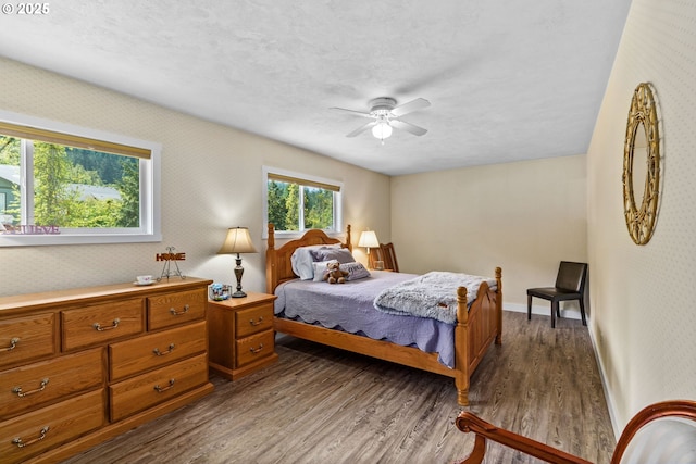 bedroom featuring baseboards, a ceiling fan, dark wood-style flooring, and a textured ceiling