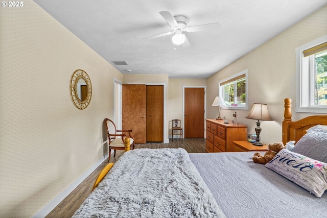bedroom with wood finished floors, multiple windows, and wallpapered walls
