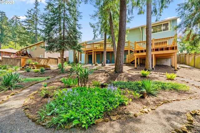back of house featuring fence, a wooden deck, and stairs